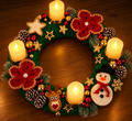 Grüner Weihnachtskranz mit roten Häkelblüten, Schneemann, Rentier, Tannenzapfen und vier leuchtenden Kerzen.